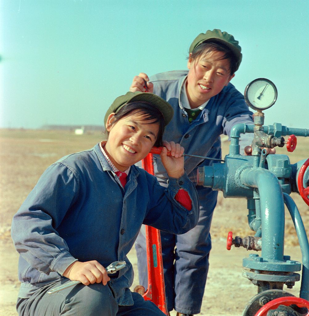 A member of the Gudao Women's Oil Production Team hears crude oil flowing in Dongying, Shandong Province, 1975.