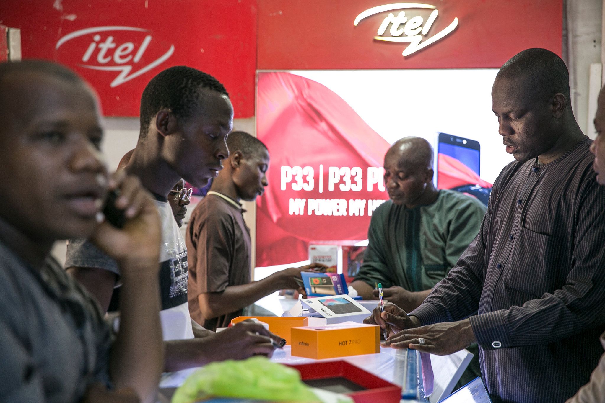 A worker assists customers as they inspect smartphone handsets at a telecoms store in Maiduguri, Nigeria.