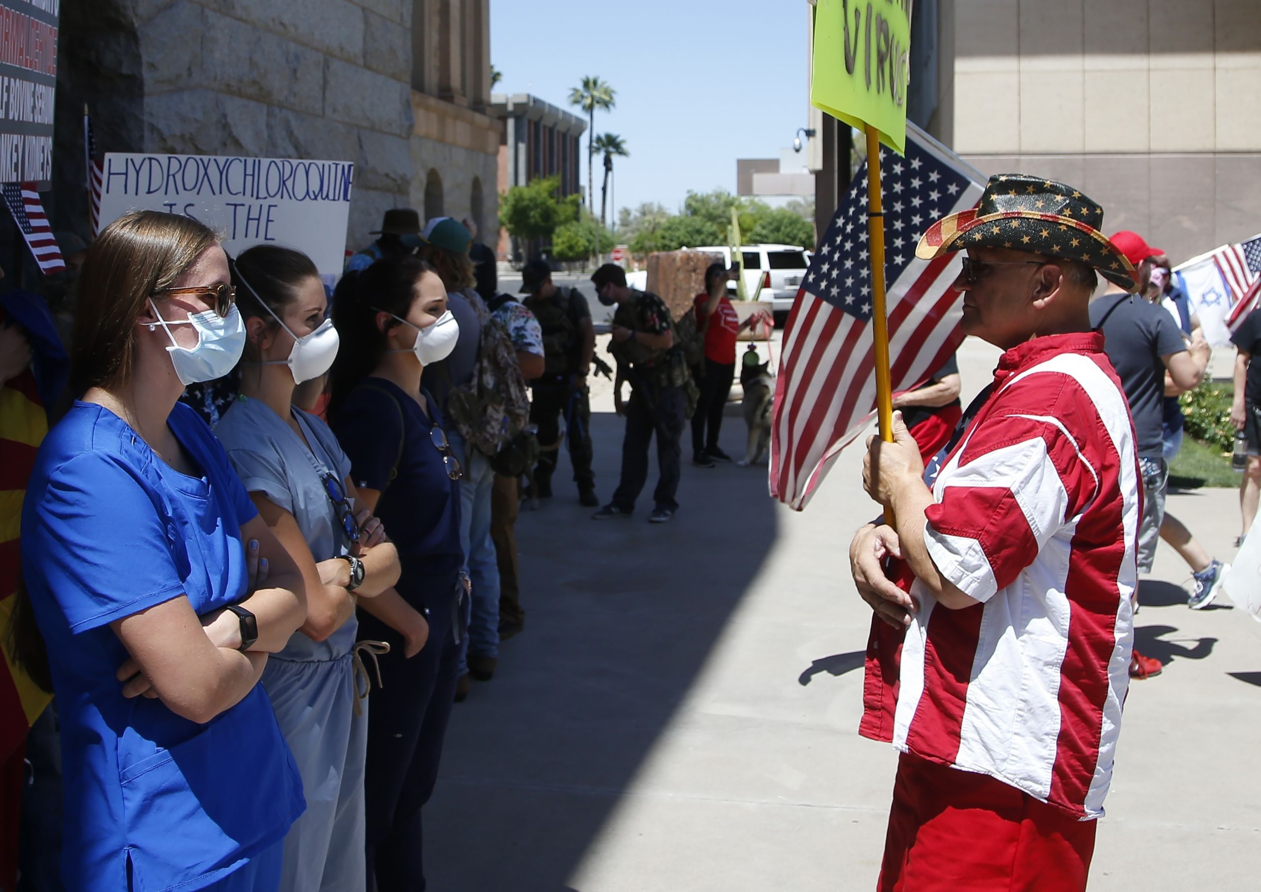 Counter-protesting caregivers face a protester rallying to 're-open' Arizona, April 2020.